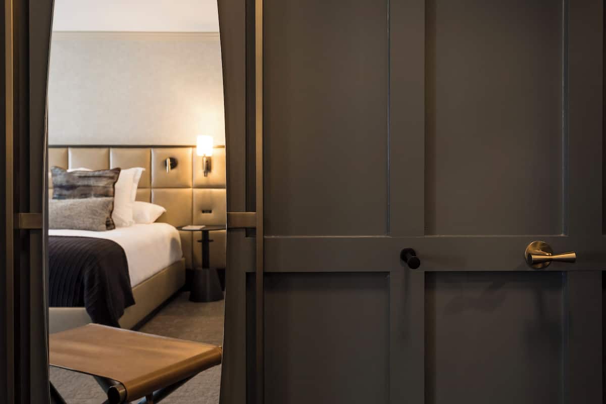 Ein Hotelzimmer mit Bett, Nachttisch, Lampe und einer Tür.
