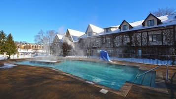 Una piscina con una fuente acuática, rodeada de edificios con tejados nevados.