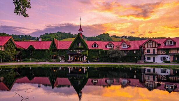 Un hotel a orillas del lago con arquitectura tradicional, una torre central y un reflejo en el agua.