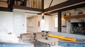 Una sala de estar con chimenea, una escalera y vistas al exterior.