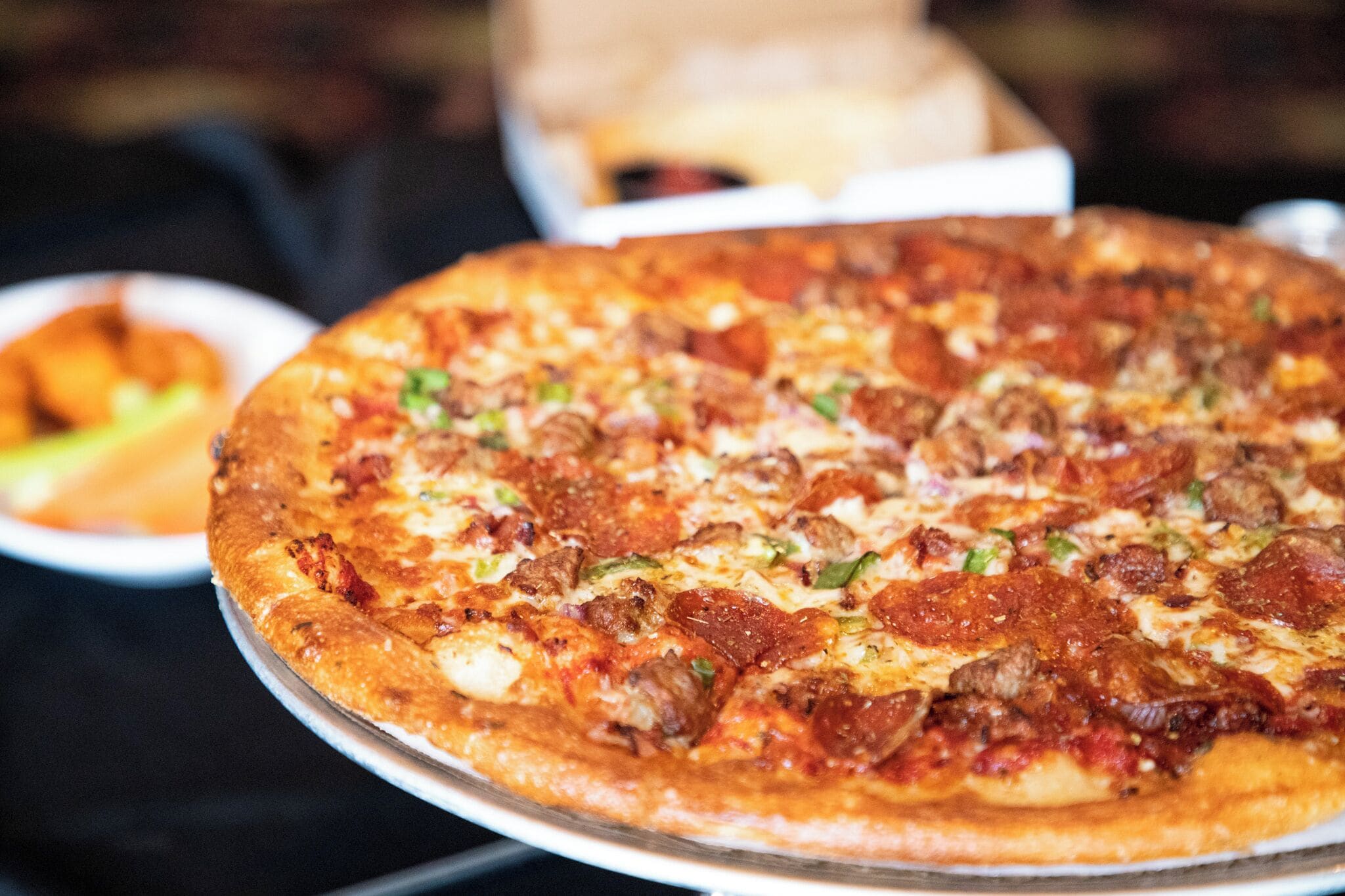 A large pizza with various toppings on a metal tray.