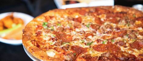 A large pizza with various toppings on a metal tray.