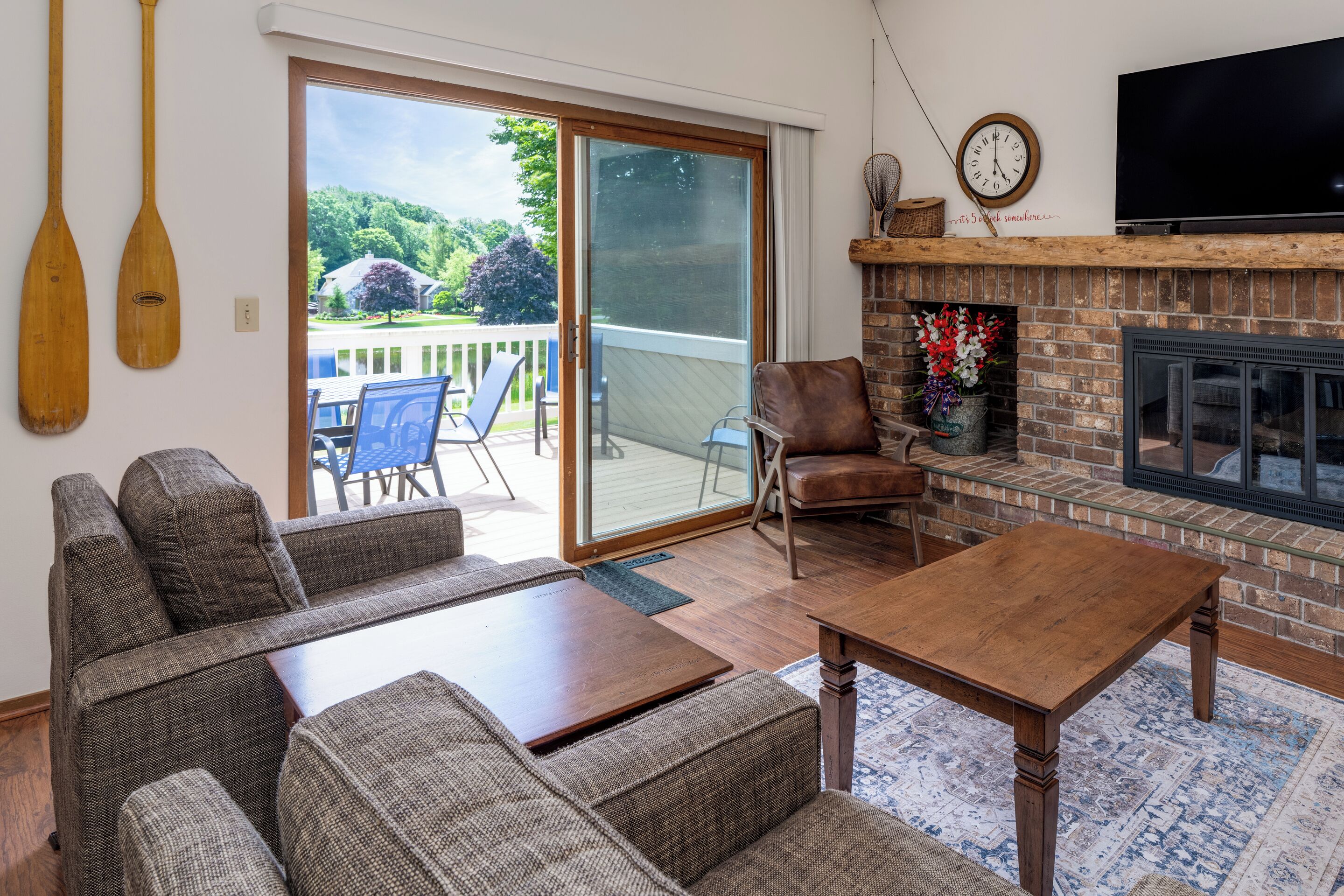 A living room with a sofa set, a wooden coffee table, a fireplace, a TV, and a sliding glass door leading to a balcony.