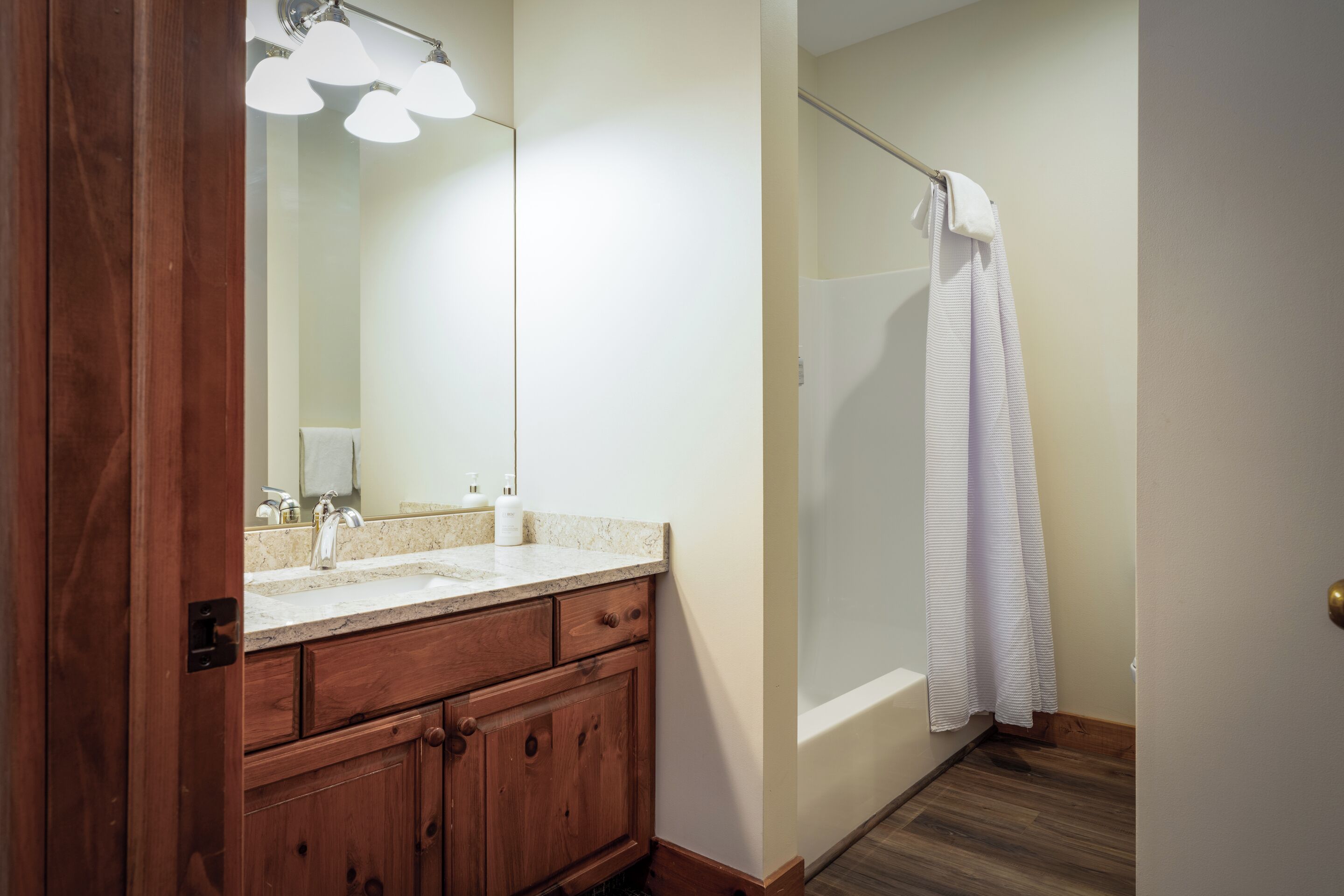 A bathroom with a wooden vanity, a mirror, a shower curtain, and a bathtub.
