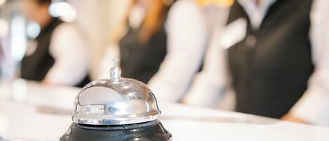 A hotel reception area with a service bell, a counter, and a blurred background of staff.