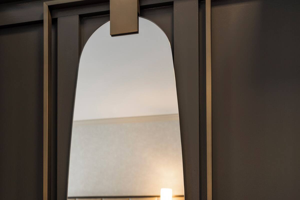 Ein Hotelzimmer mit Bett, Nachttisch, Lampe und Blick durch einen Türrahmen.