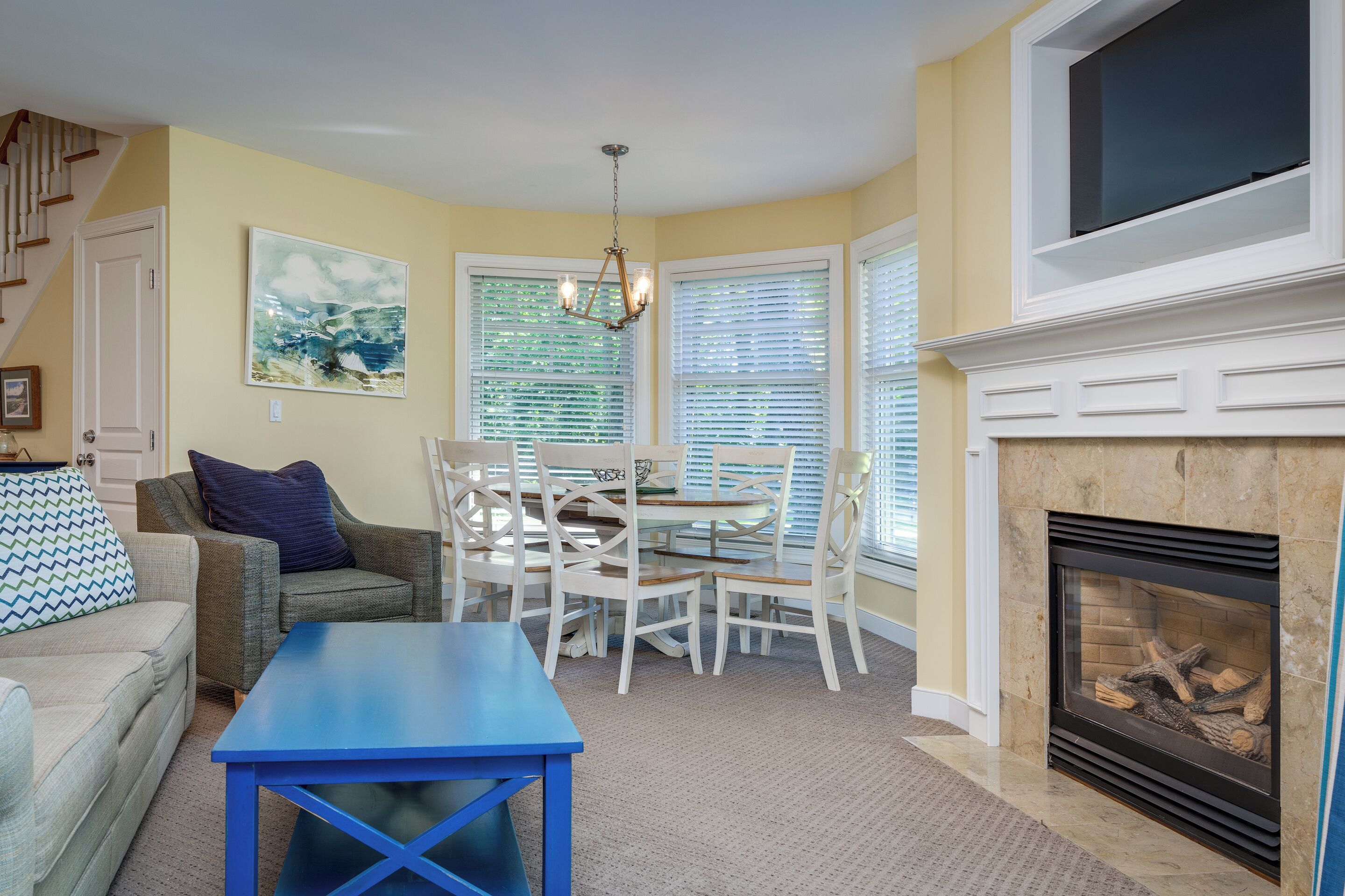 A living room with a sofa, a blue table, a fireplace, and a dining area with chairs and a table.