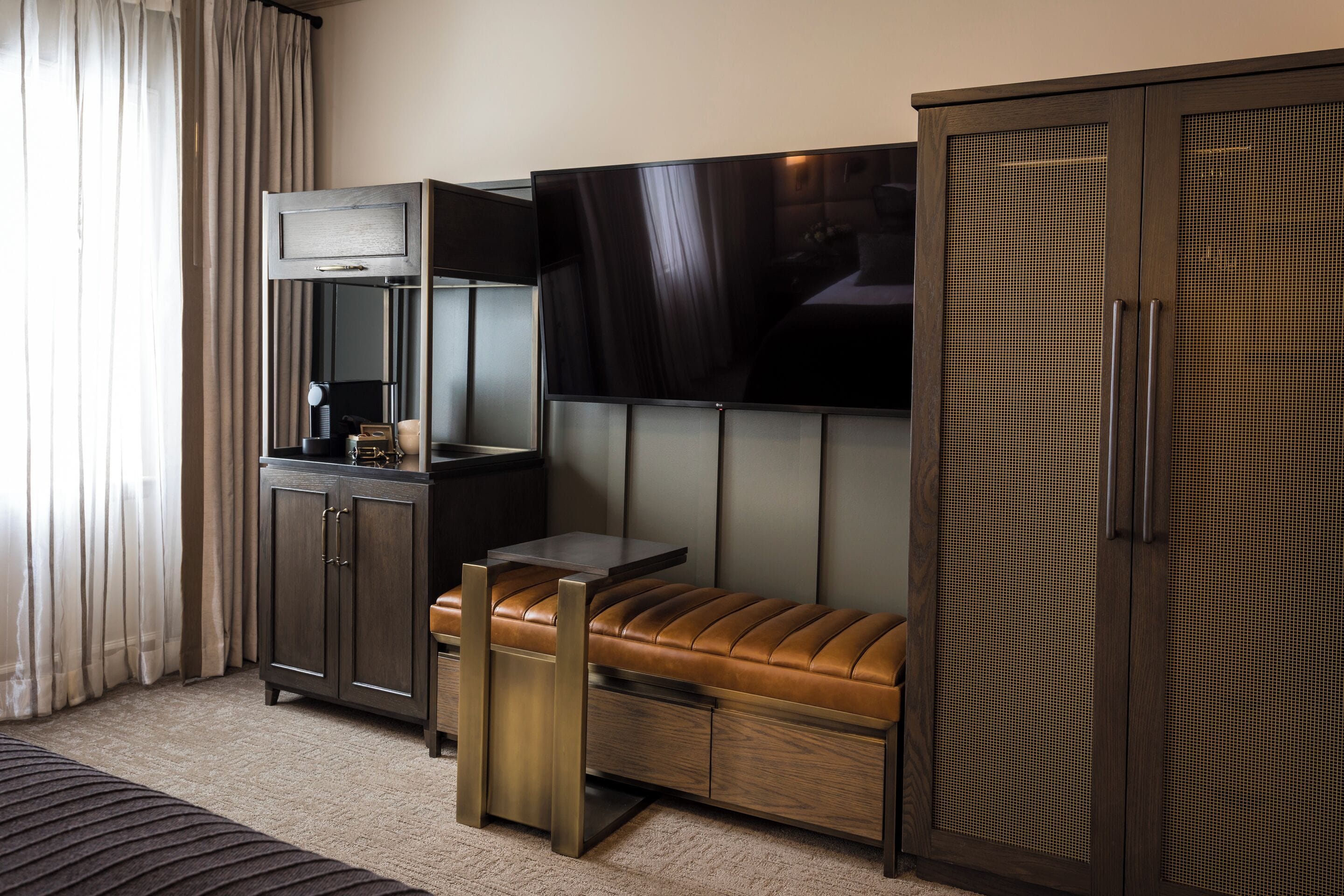 A hotel room with a sofa, a TV, a cabinet, and a large wardrobe.