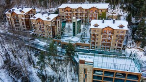 A multi-story hotel with balconies, a ski lift, and a glass-enclosed building. - Anyospark Hotel (Anyos)