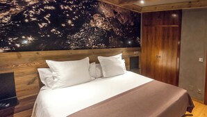 Una cama bien tendida con ropa de cama blanca y marrón, un cabecero de madera y un mural de estrellas en la pared.