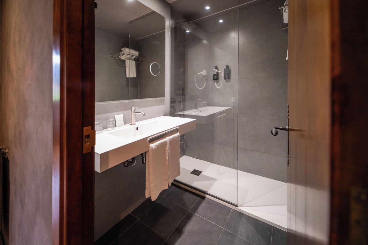 A modern bathroom with a glass shower enclosure, a vanity with a mirror, and a towel rack.