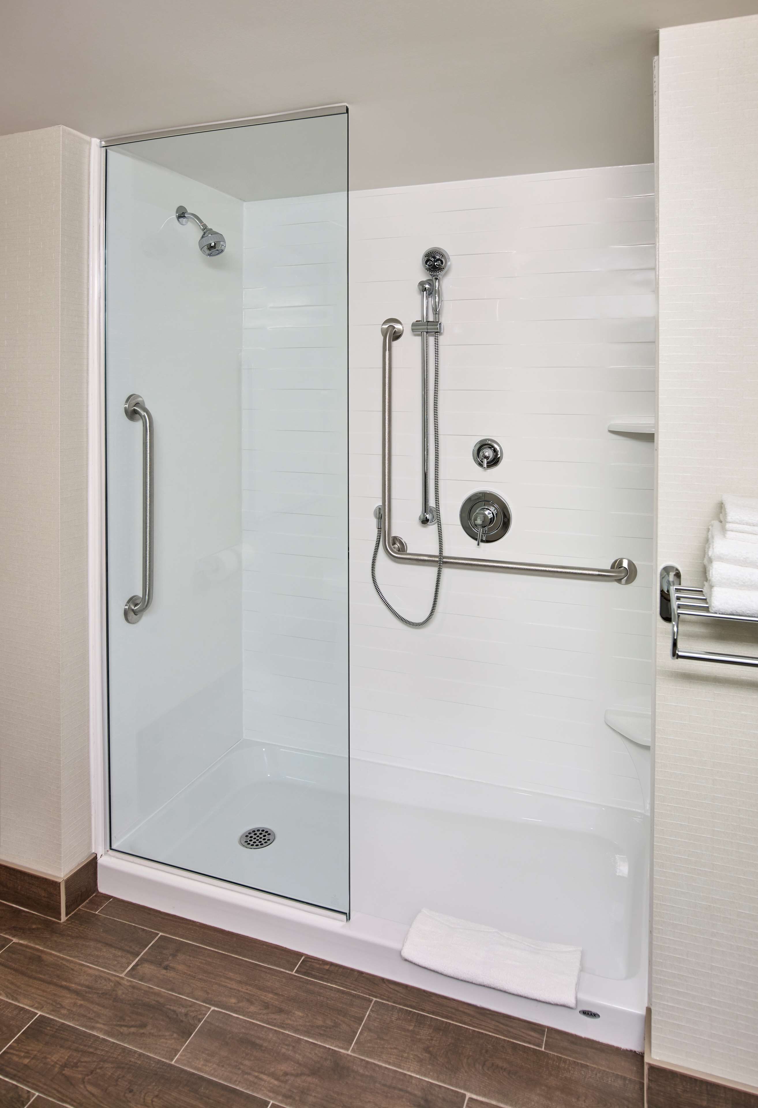 A glass-enclosed shower with a handheld showerhead, a handheld showerhead, and a handheld showerhead.