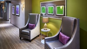 A hotel lobby with two grey armchairs, a small round table with a lamp, and framed artwork on the wall. - Hampton Inn by Hilton Sarnia/Point Edward (Sarnia)