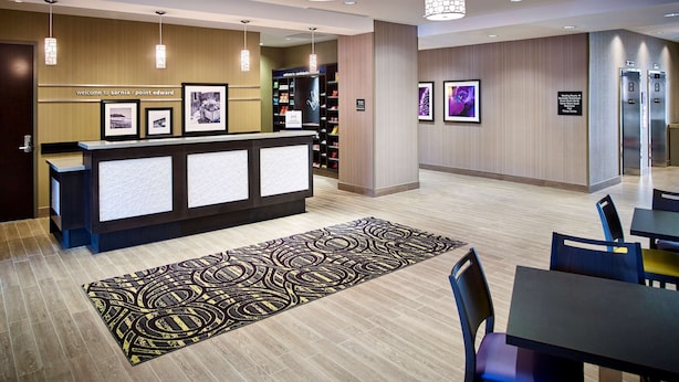 A hotel reception area with a reception desk, framed pictures on the wall, and a patterned rug on the floor. - Hampton Inn by Hilton Sarnia/Point Edward (Sarnia)