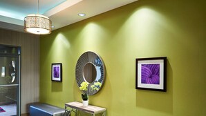 A modern waiting area with a green wall, two benches, a round mirror, and framed artwork. - Hampton Inn by Hilton Sarnia/Point Edward (Sarnia)