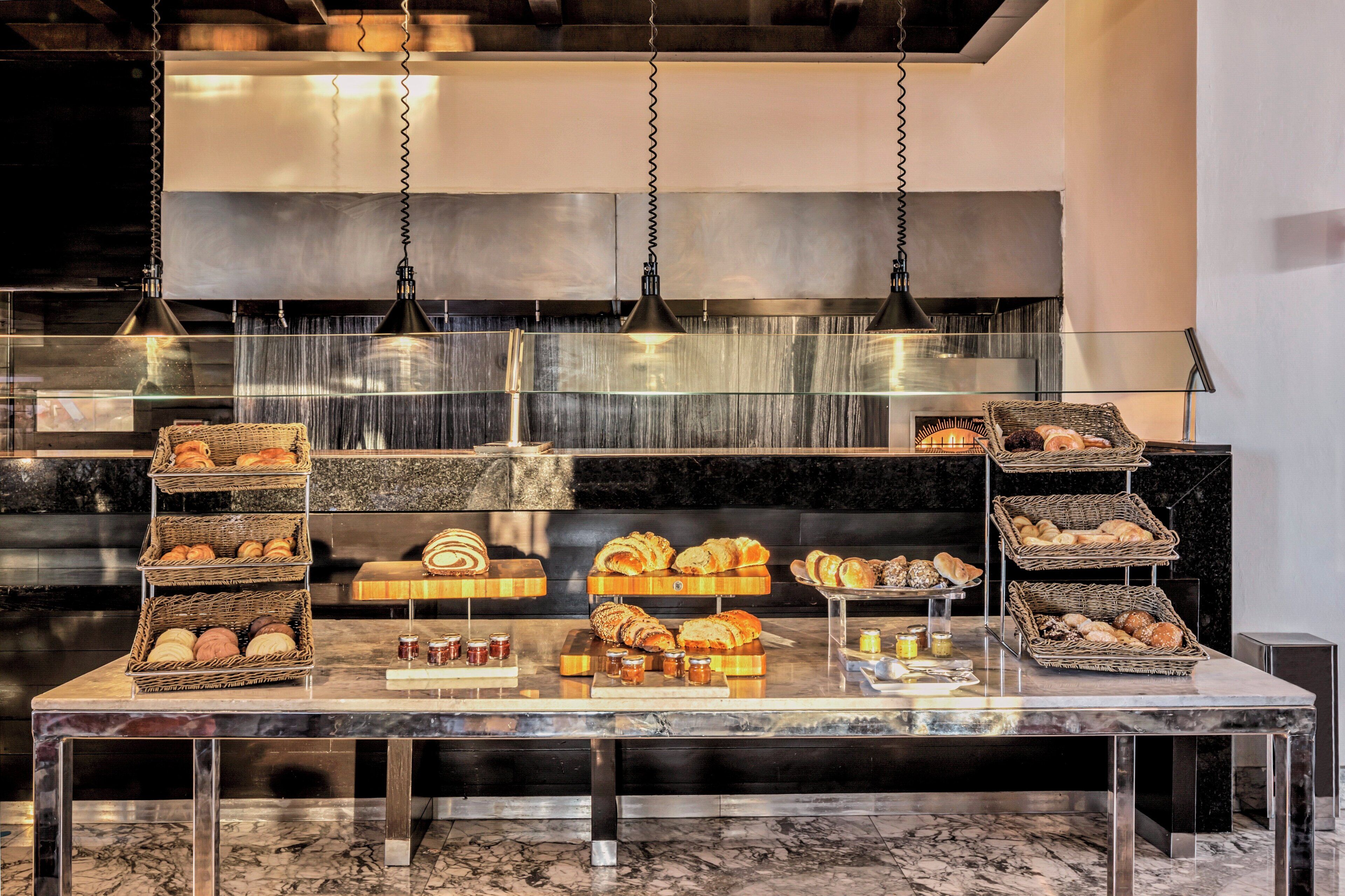 A bakery display with various breads and pastries on a marble countertop.