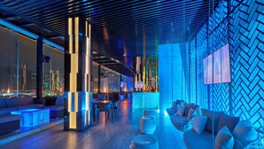 Een moderne lounge met zitplaatsen, een bar en uitzicht op de stad.