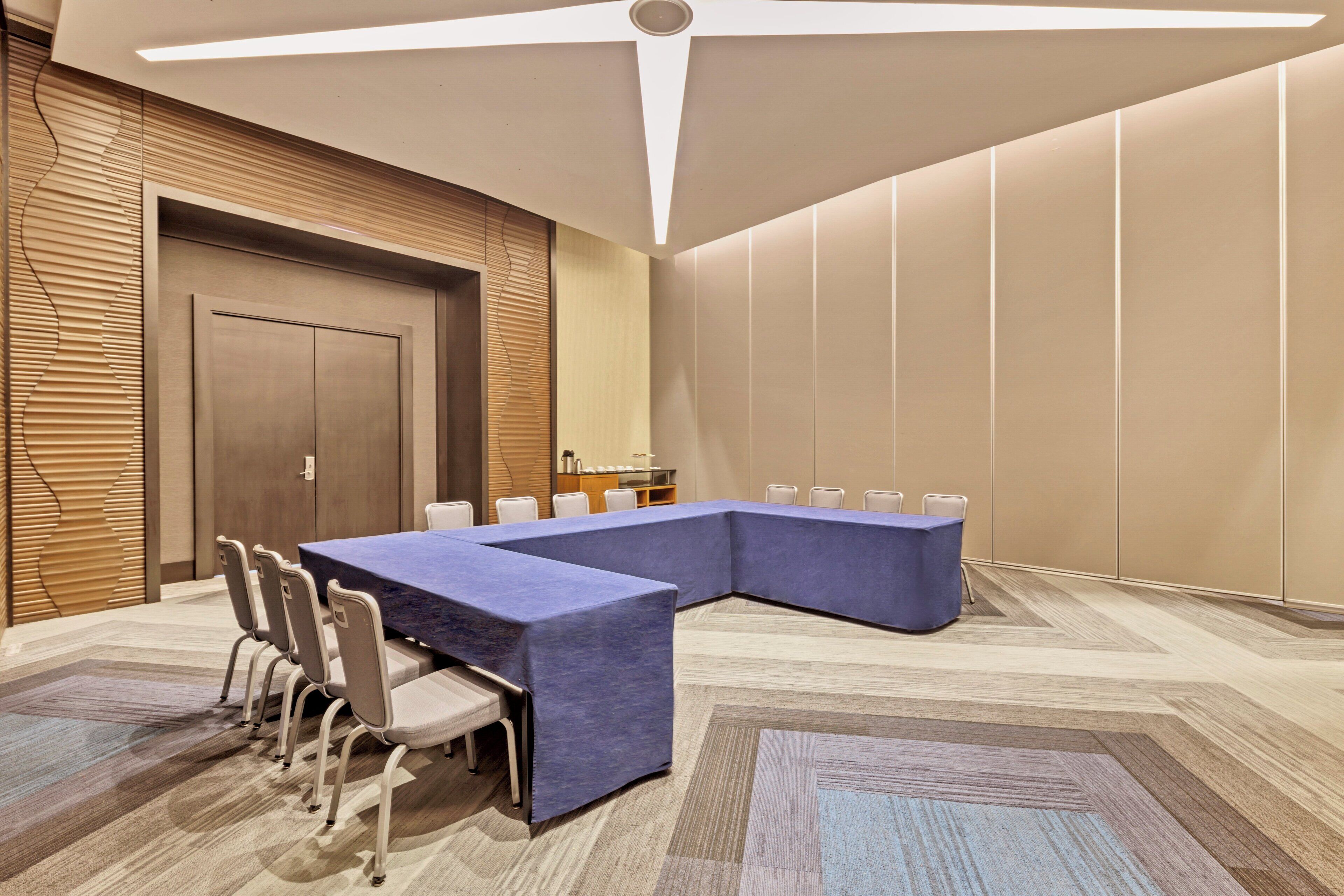 A conference room with a long table, chairs, and a wooden door.