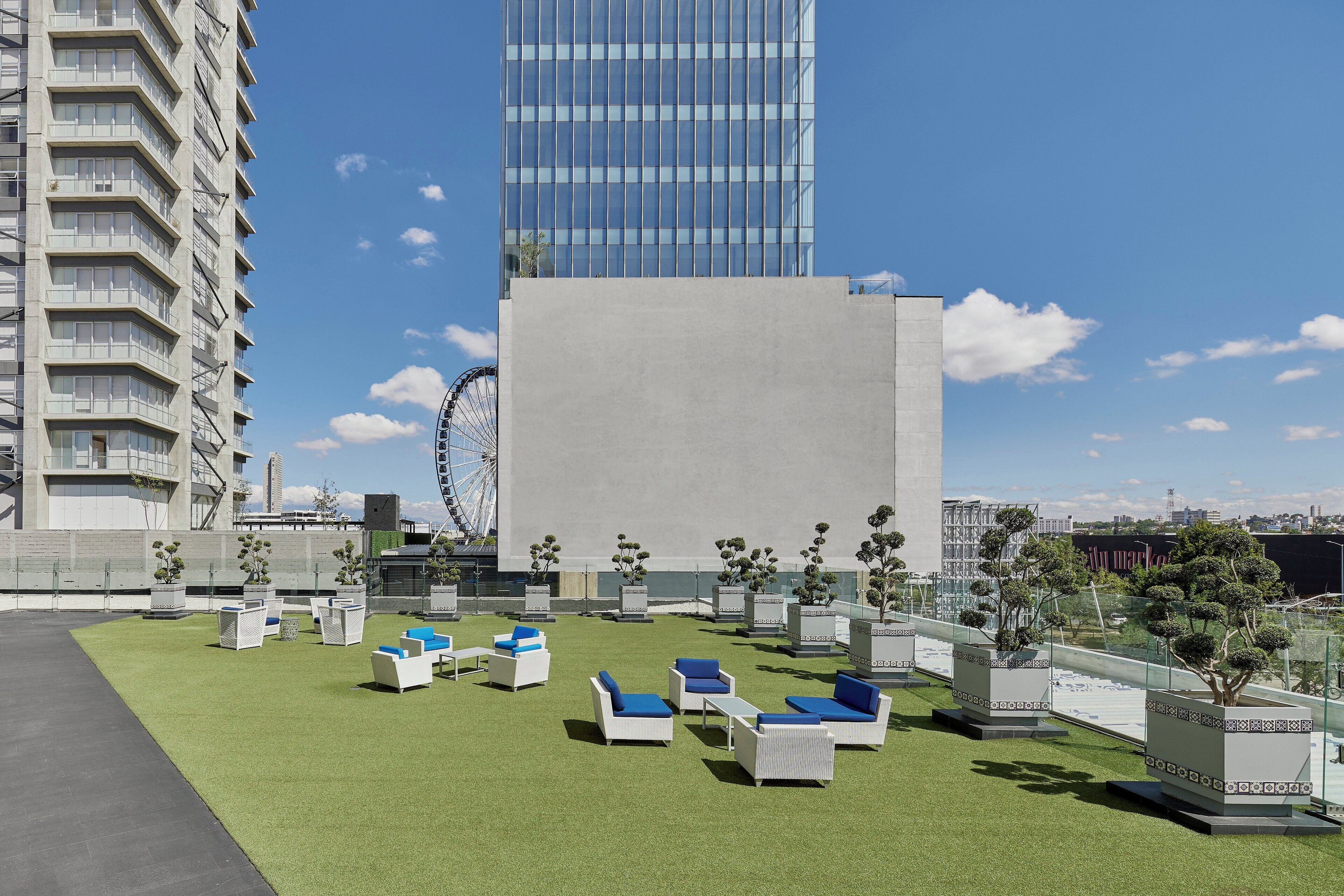 A rooftop terrace with outdoor seating and a Ferris wheel in the background.