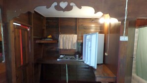 A compact kitchen with wooden walls, a sink, and a refrigerator. - Beach Road Cottages at Jah Bs (Negril)