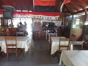 A rustic eatery with wooden tables and chairs, a chalkboard menu, and a sign reading "JAH'S Village House". - Beach Road Cottages at Jah Bs (Negril)