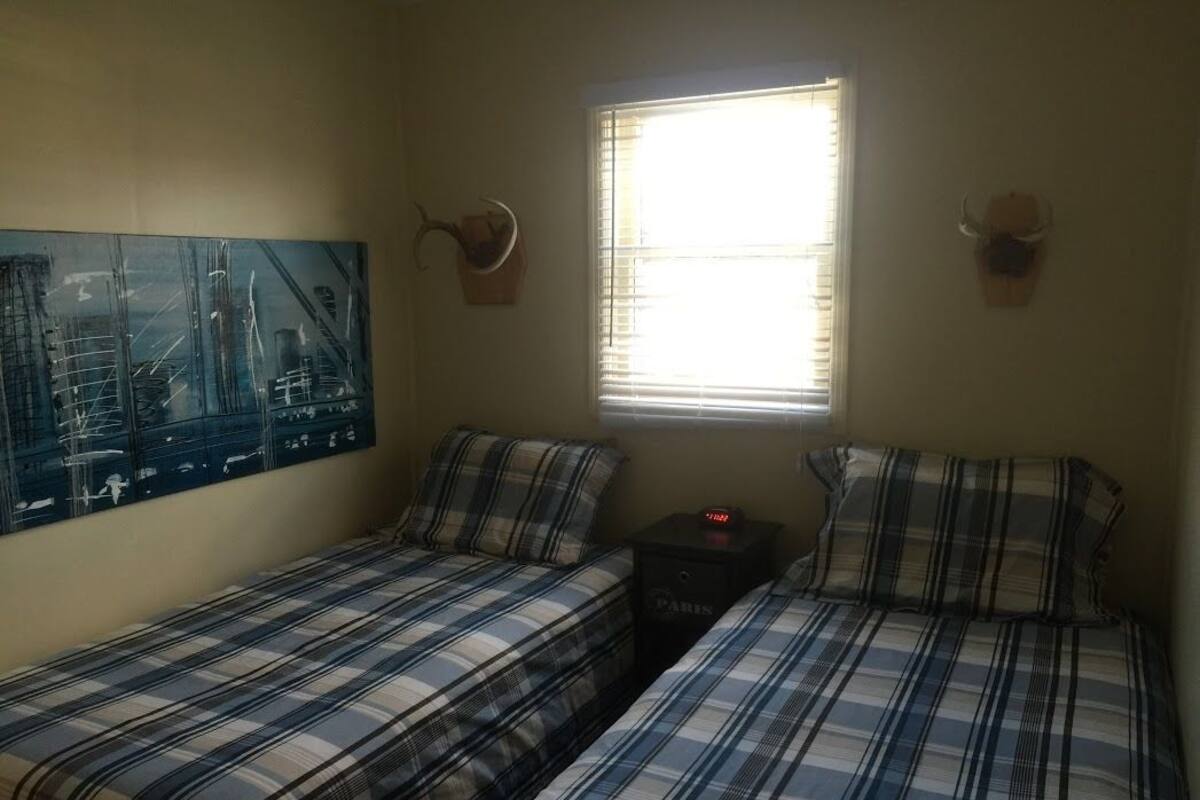 Una habitación con dos camas, una ventana y un cuadro en la pared.
