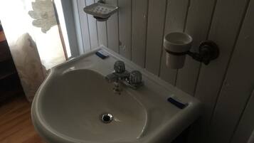 A bathroom with a white sink, a soap dish, and a cup holder.