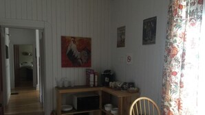 A kitchen with wooden cabinets, a dining table, and a painting on the wall. - Hôtel du Chasseur (Brownsburg-Chatham)