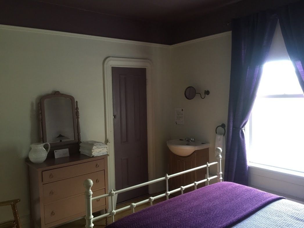 Un dormitorio con cama, cómoda, espejo y ventana con cortinas.