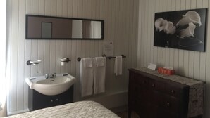 A bathroom with a sink, mirror, and a towel rack. - Hôtel du Chasseur (Brownsburg-Chatham)