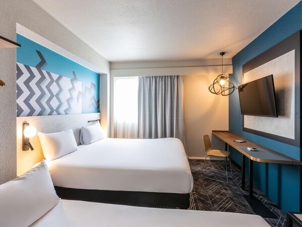 Habitación de hotel con una cama grande, un escritorio, un televisor y una lámpara moderna.