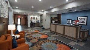 A hotel lobby with a reception desk, seating area, and a decorative rug.