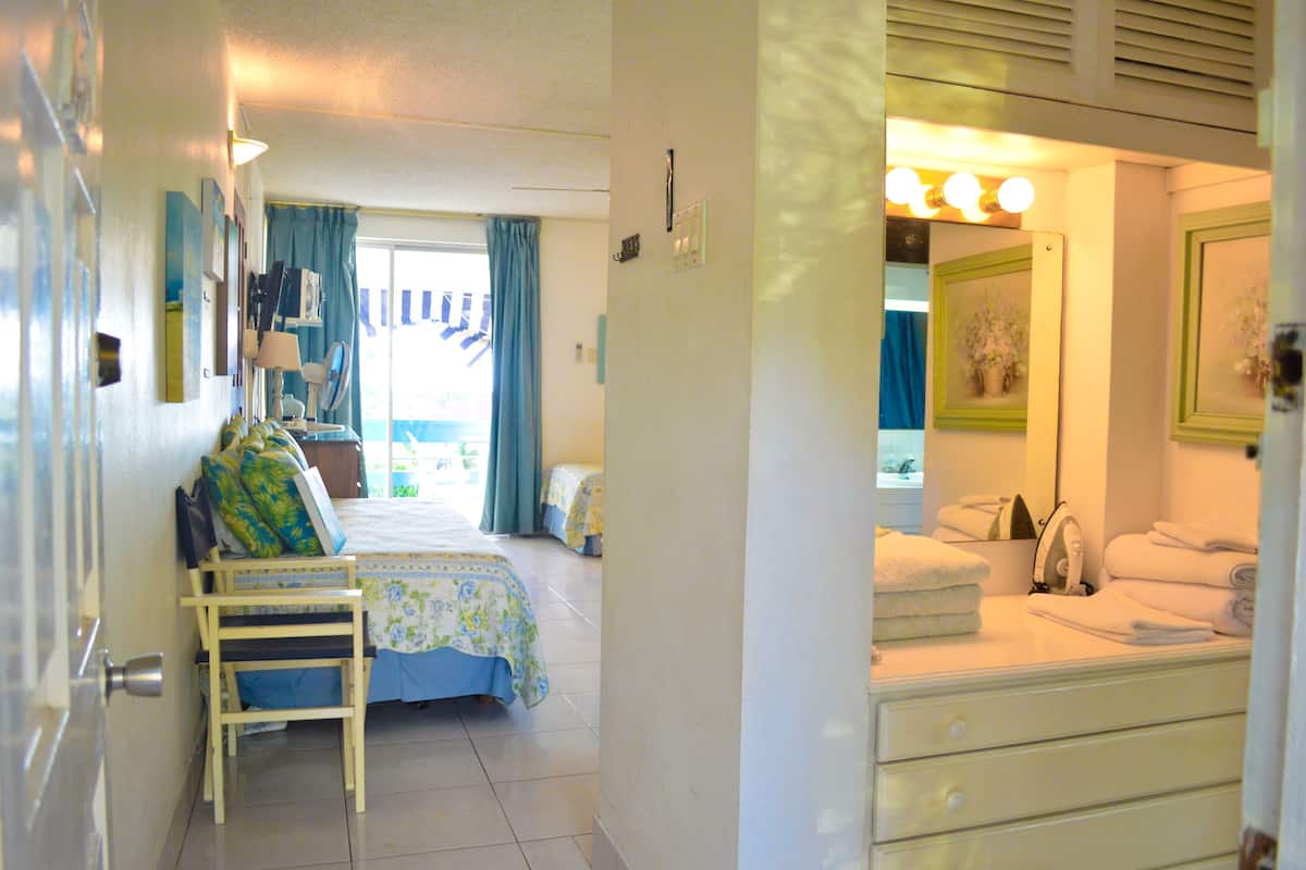 Un dormitorio con una cama, una silla, un aparador y un espejo.