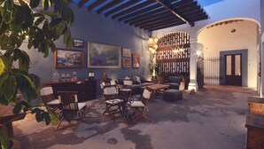 Un patio exterior con una pérgola de madera, zona de estar y obras de arte en las paredes.