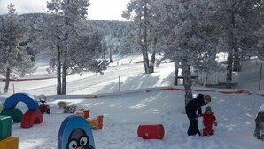 A snowy outdoor area with play structures, including a large penguin figure and colorful playhouses. - Albergue Rural Ca L'anton (Sort)