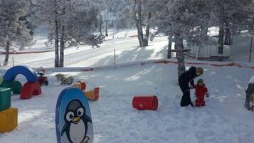 Winter wonderland awaits at this serene outdoor space, featuring snow-covered trees, a clear sky, and fun snow play structures.