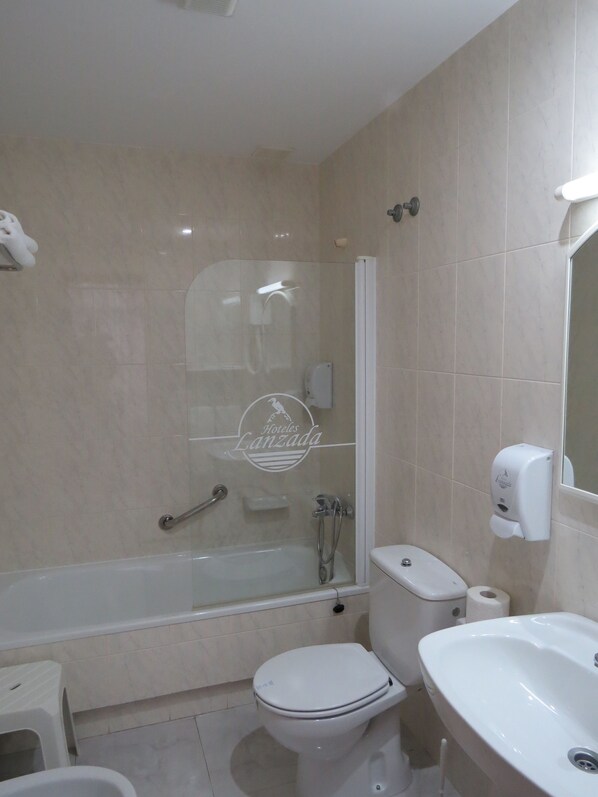 Un baño moderno con ducha acristalada, inodoro y lavamanos.