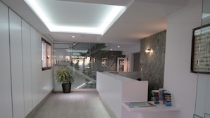 Un moderno vestíbulo de hotel con una recepción, una escalera y una planta en maceta.