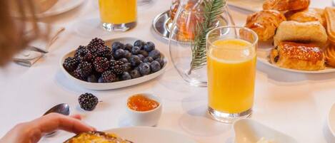 Una mesa de desayuno con una variedad de alimentos, como tostadas, fruta y pasteles.