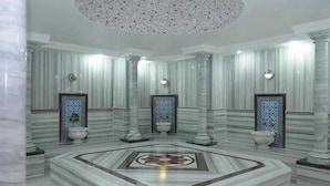 A luxurious room with marble walls, a central circular marble floor, and decorative columns.