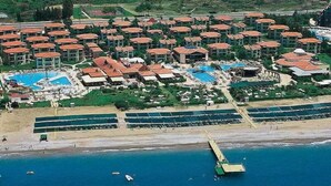 An aerial view of a resort with multiple buildings, a beach, and a pier.