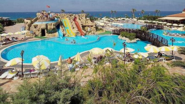 A resort pool area with multiple water slides, lounge chairs, and umbrellas.