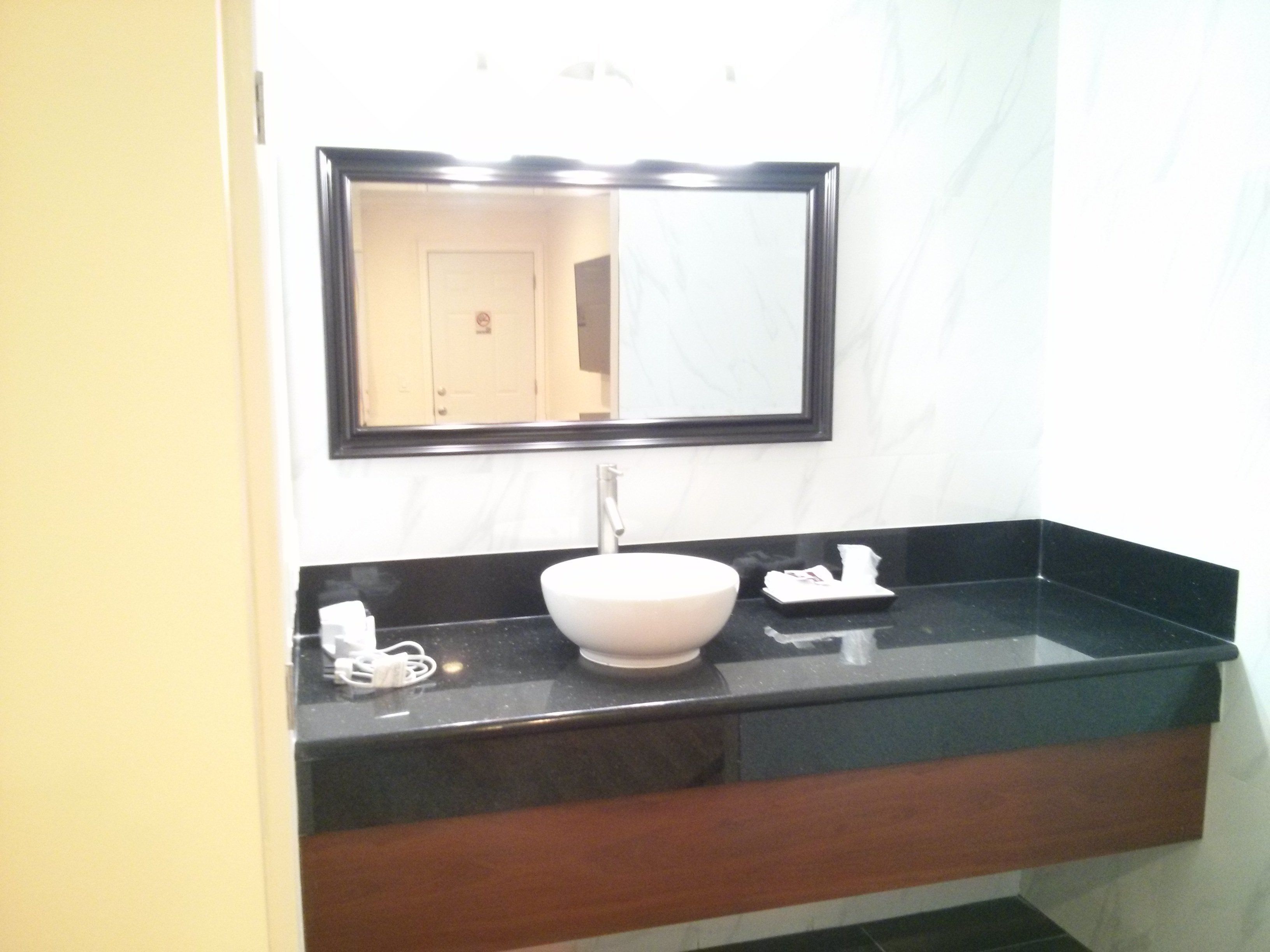 A bathroom with a black countertop, a white sink, and a mirror above it.