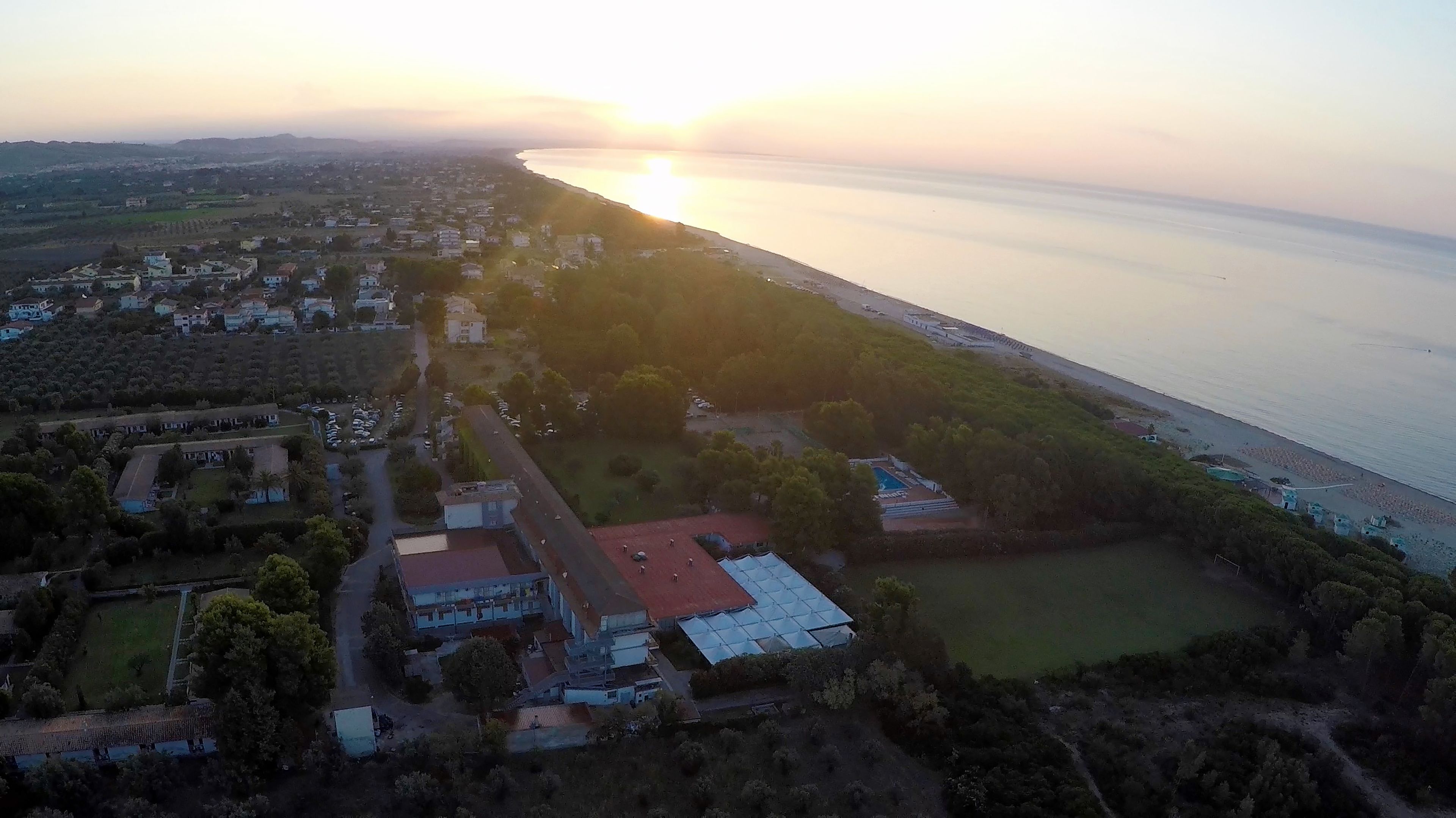 Vista aerea di una zona costiera con edifici residenziali, una strada e una spiaggia.