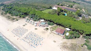 An aerial view of a beach resort with a large sandy beach, numerous sun loungers, a swimming pool, and a building complex with multiple rooms. - Villaggio Triton - Aurum Hotels (Sellia Marina)