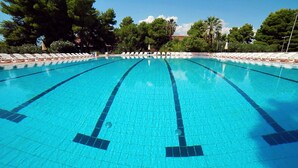 A clear blue swimming pool with white lounge chairs and umbrellas, surrounded by trees. - Villaggio Triton - Aurum Hotels (Sellia Marina)
