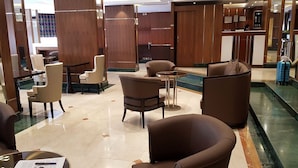 Eine Hotlellobby mit Ledersesseln, einem Empfangstresen und einer Glastrennwand.