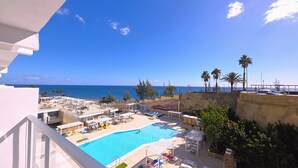 A pool area with lounge chairs, a swimming pool, and a view of the sea. - Europalace (San Bartolomé de Tirajana)