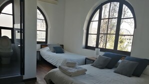 A hotel room with two beds, a bathroom, and large arched windows. - El Museo Hotel Boutique (La Paz)