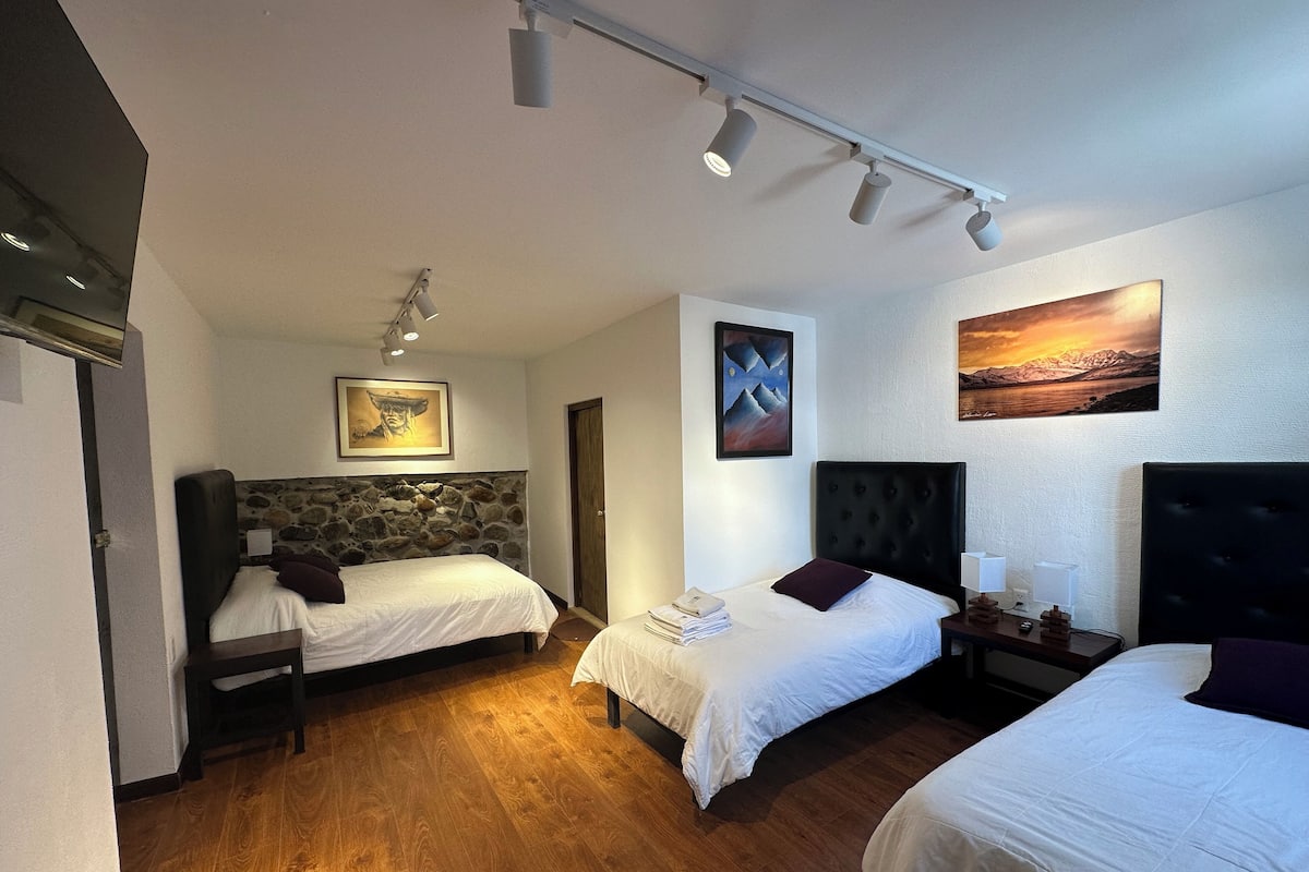 A hotel room with two beds, a stone headboard, a painting, and a view of a mountain landscape.